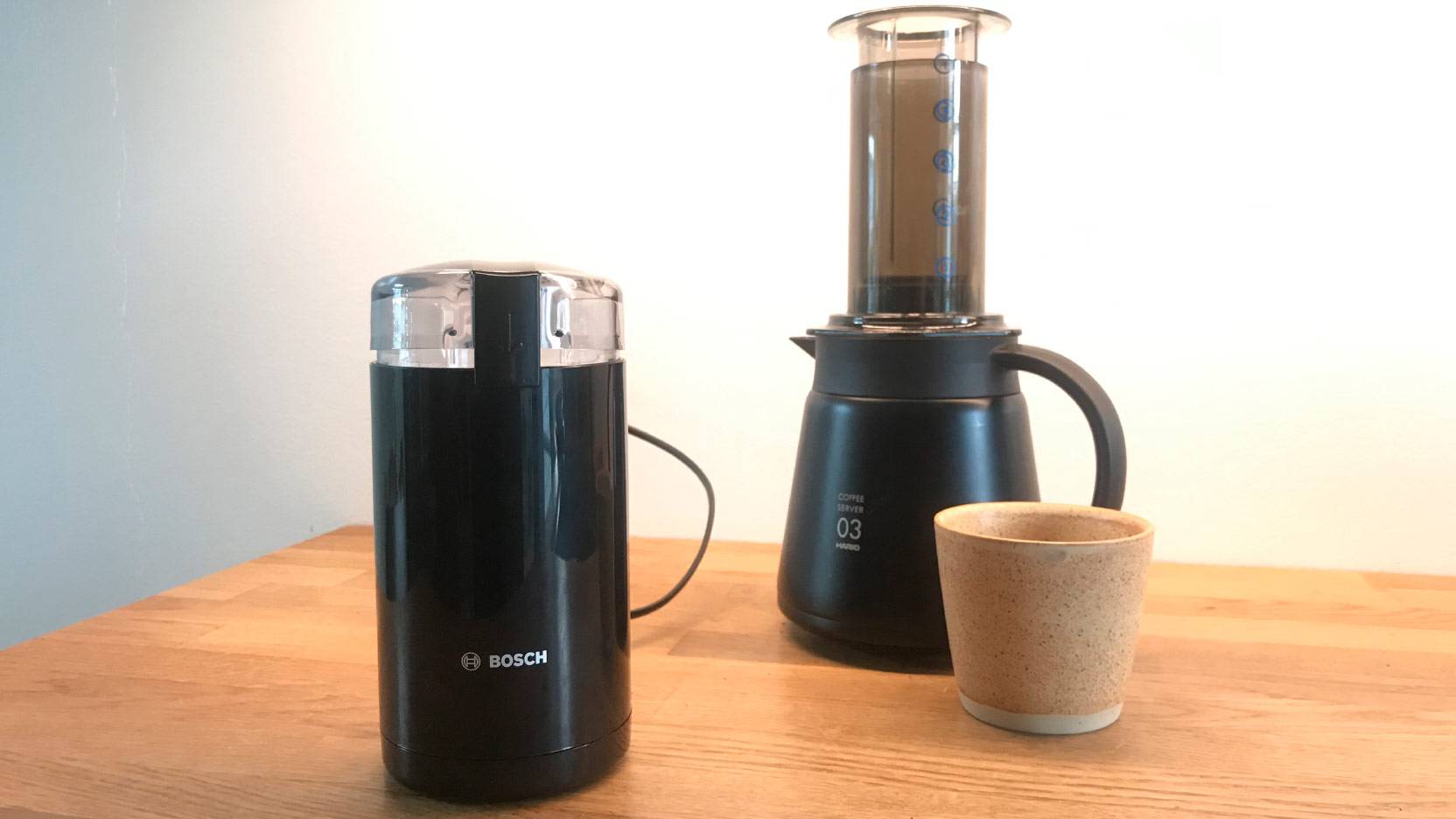 Billede af Bosch TSM6A013 kaffemølle på køkkenbord med Hario AeroPress i baggrunden