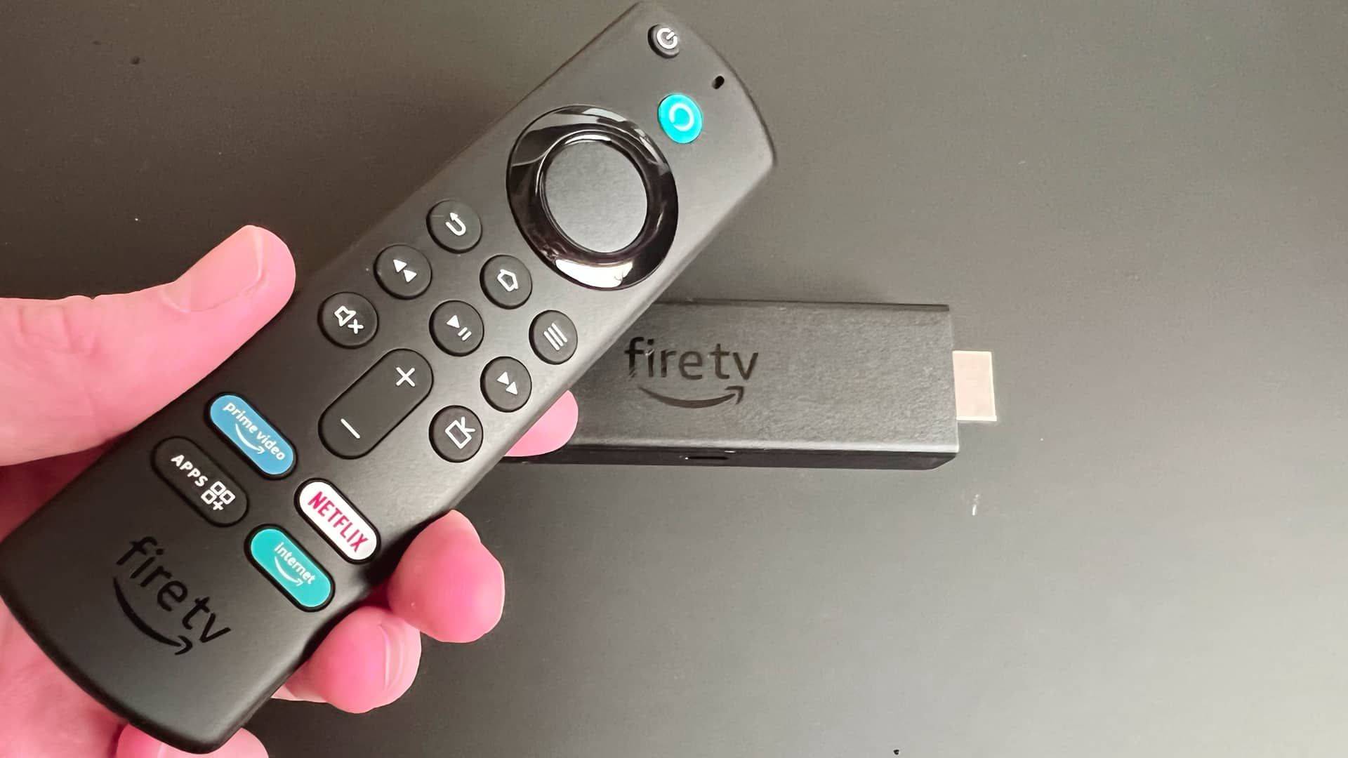 Billede fra test af medieafspiller Amazon Fire TV Stick 4K Max fjernbetjeningen i hånden og Fire TV sticken i baggrunden